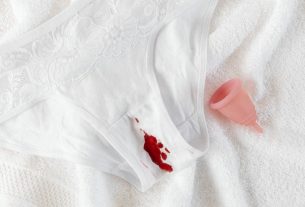 A menstrual cup alongside stained underwear on a clean towel, symbolizing menstrual health.
